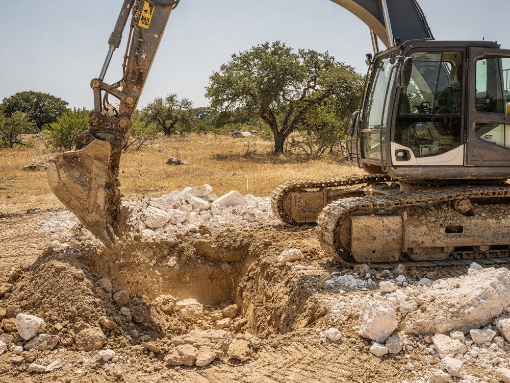 Excavator digging a foundation pad on an Austin, TX lot
